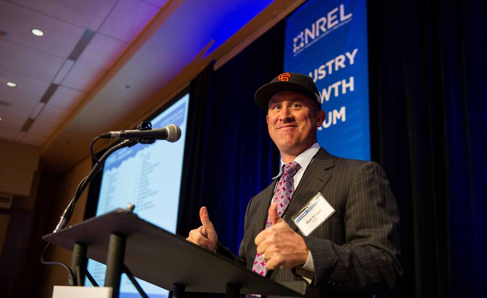 ringer-hat-body Ringer gives a thumbs up while standing behind a podium