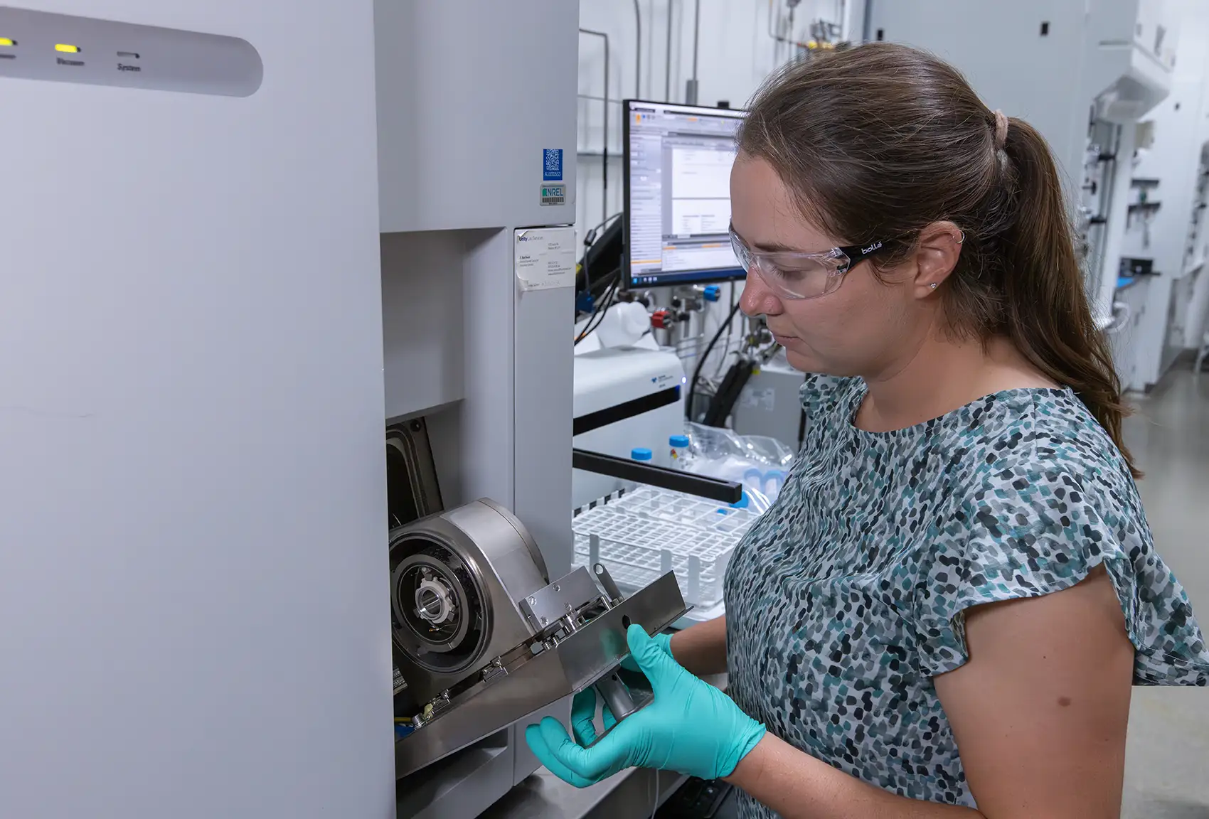 20260127-early-career-spotlight-from-coastal-curiosity-to-catalyst-discovery-how-melissa-kreider-found-her-element-101821 A woman with safety goggles interacts with electrolyzer testing equipment.