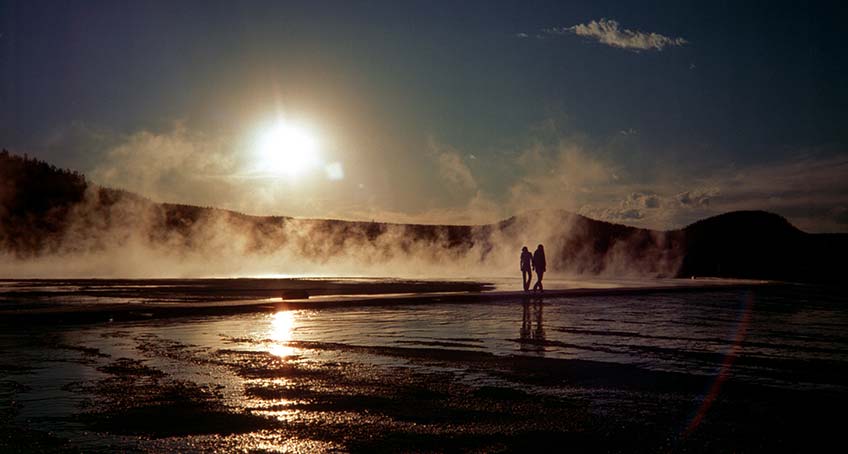 Couple walking on the beach, set against the sunset.