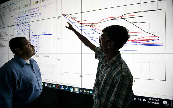 research-areas-52720 Two researchers review a large projection of a multi-timescale simulation environment.