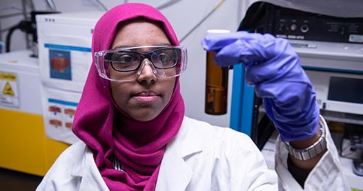 A researcher in a lab holding a test tube.