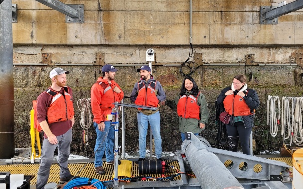 Group of people in life jackets stand on marine vessel