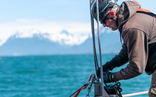 Person stands on side of vessel ready to deploy a marine energy device