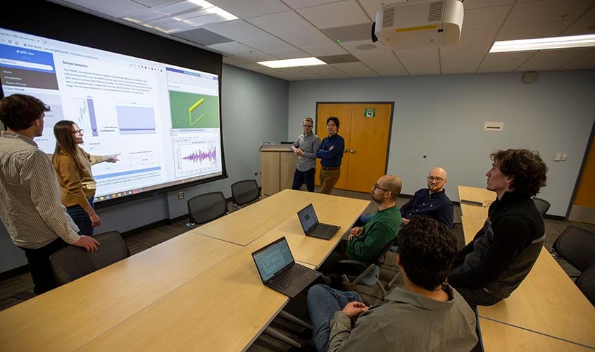 A room of researchers considering a projected screen.