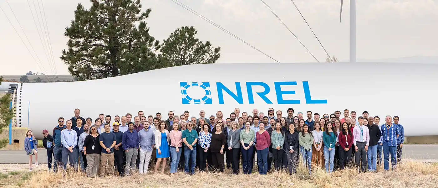 Staff standing in front of wind turbine blade on ground