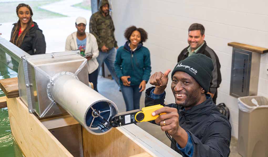 pipeline-pathways-tn Person holds a thumbs up while checking out a technical devices while others stand around.