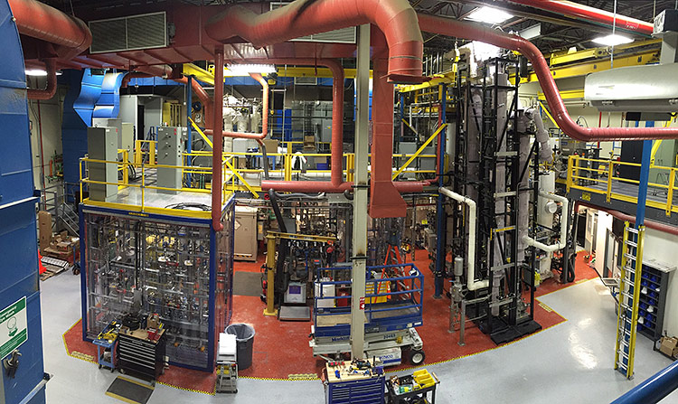 Engineers walk and work among the pipes and tubes of NREL’s Thermal and Catalytic Process Development Unit.