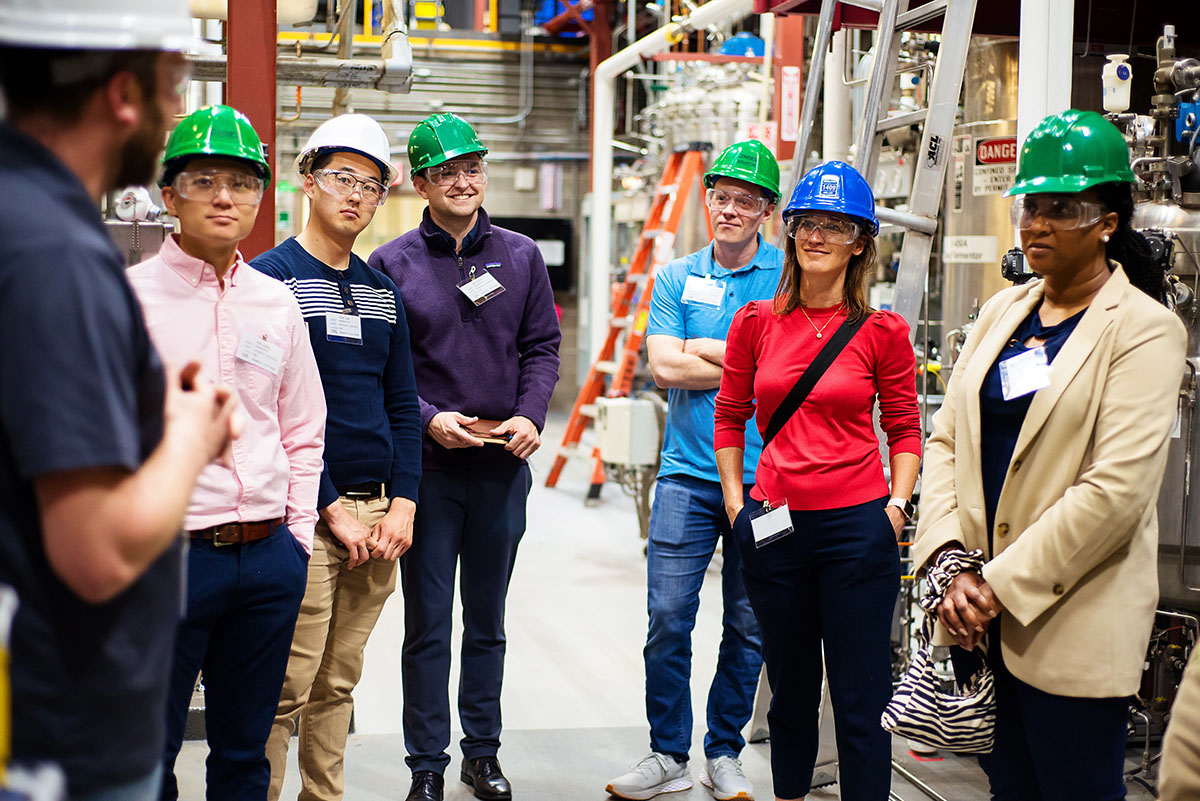 A group of people in hard hats visit a laboratory.