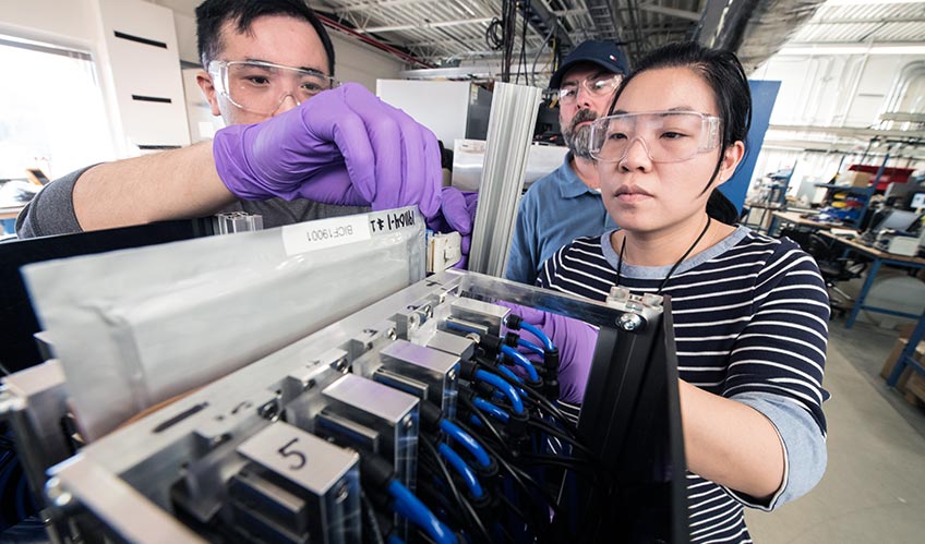 Three researchers work on an acoustic device.