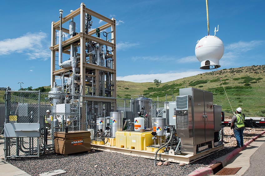Crews crane a natural gas storage vessel into place in a bioreactor.