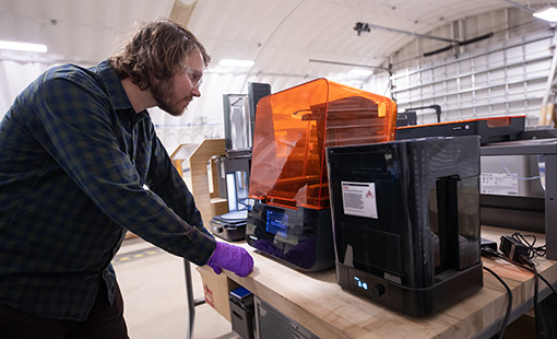 Researcher examines a 3D printer in process.