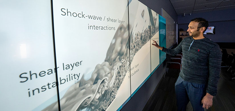 A person looks at a model of turbulence on a wall-sized screen.