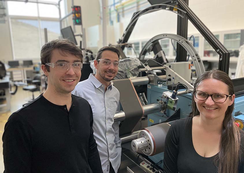 Three researchers in goggles in front of a machine.