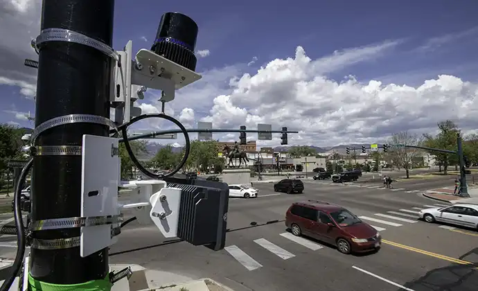 Scientific equipment attached to a pole near a traffic intersection.