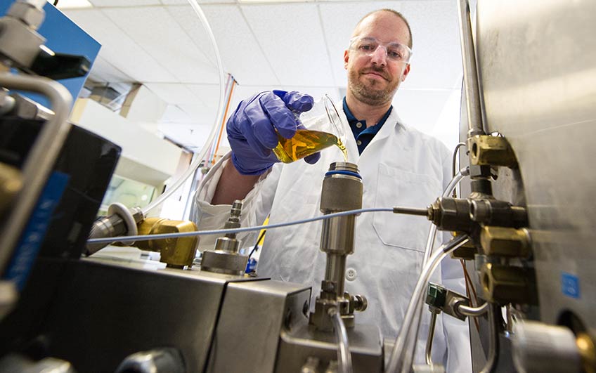32870-848w A researcher in a lab pours fuel into an ignition quality tester.