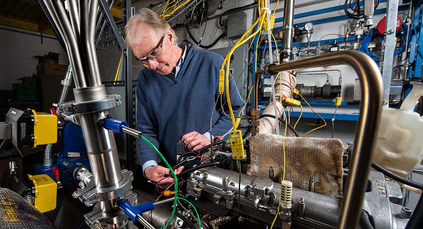 54810-848w A researcher works on a 4-cylinder spark ignition engine that was converted into a single-cylinder engine for research purposes.