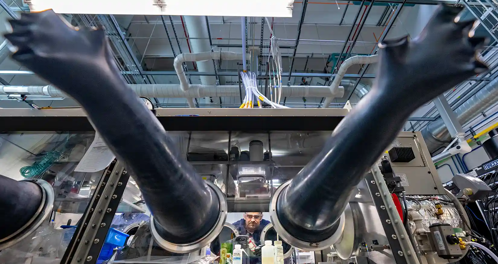 74544-bdy Researcher in a lab works in a glove box, analyzing battery assembly