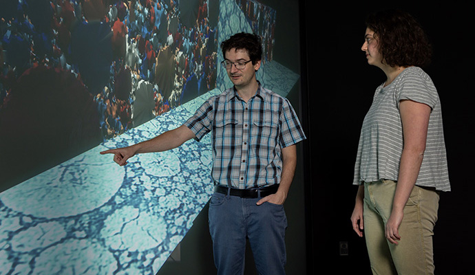Two people look at a screen in a visualization lab.