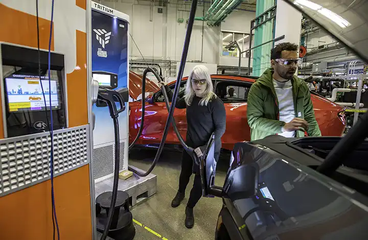 Researchers in a lab testing an electric vehicle being charged