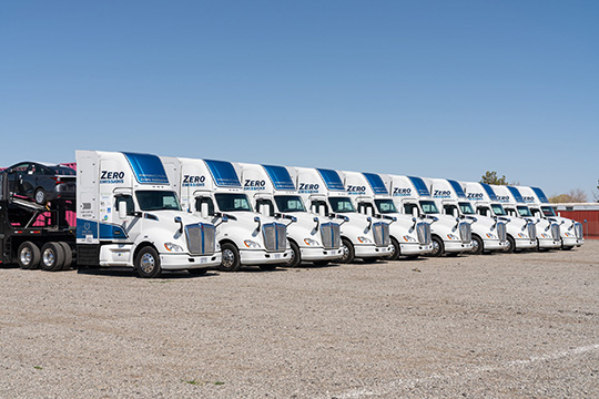fall24-90388 A fleet of zero-emission semitrucks parked next to each other.