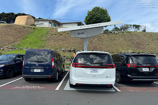fall24-dod-fleet-electrification An EV plugged into a charger powered by a solar array mounted above the charging spot.