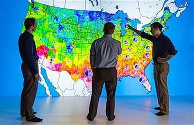 photo-35357 Photo of researchers looking at a large, colorful map of the United States.