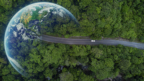 winter24-getty-1451295564 Aerial image of a car driving on pavement through a heavily wooded area toward the planet Earth faded on the left.