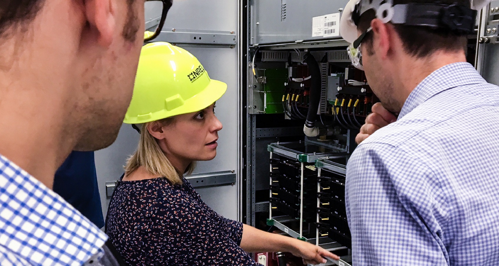 A photo of three researchers inspecting some circuitry. 