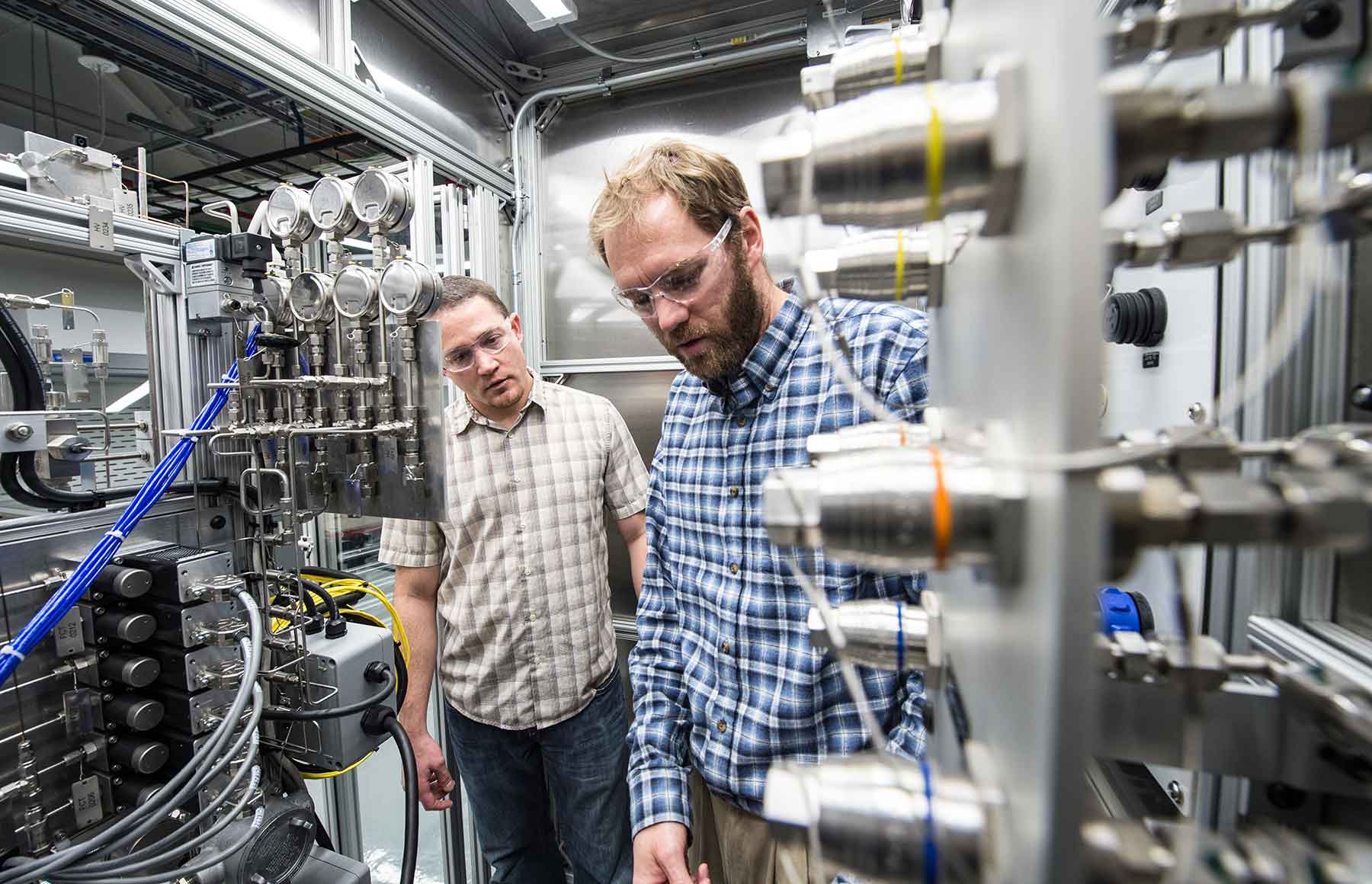 Two men examine a large piece of laboratory equipment.