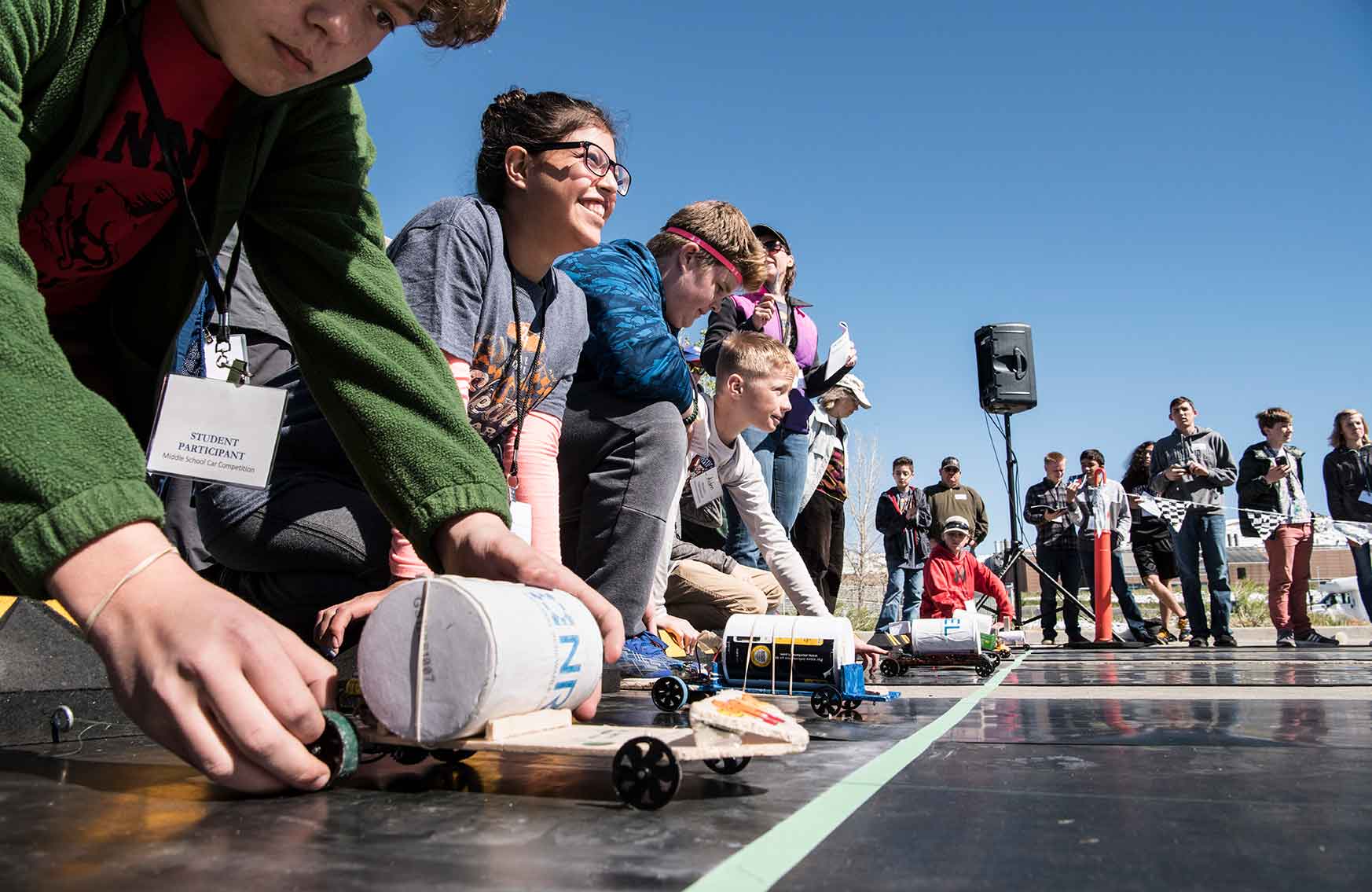 Students line up with their models cars behind the starting line.