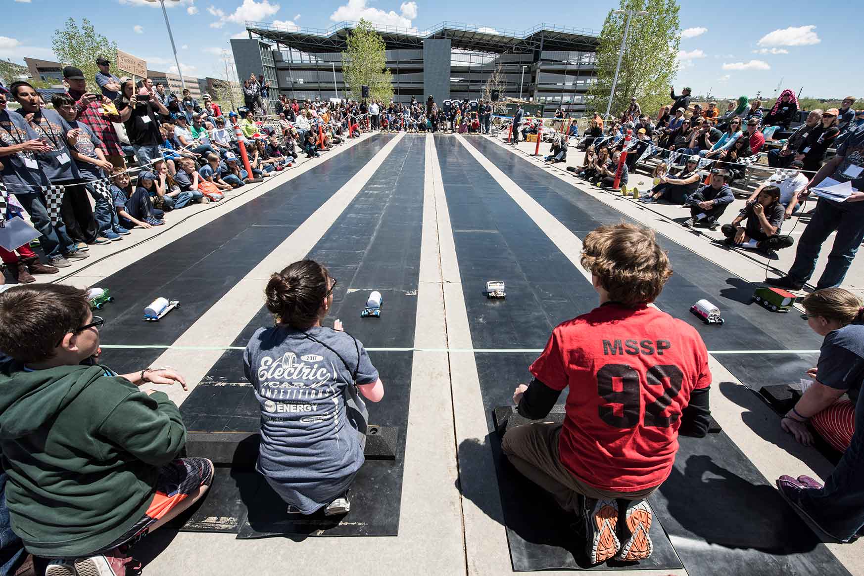 Students watch their cars race down the track toward the finish line.