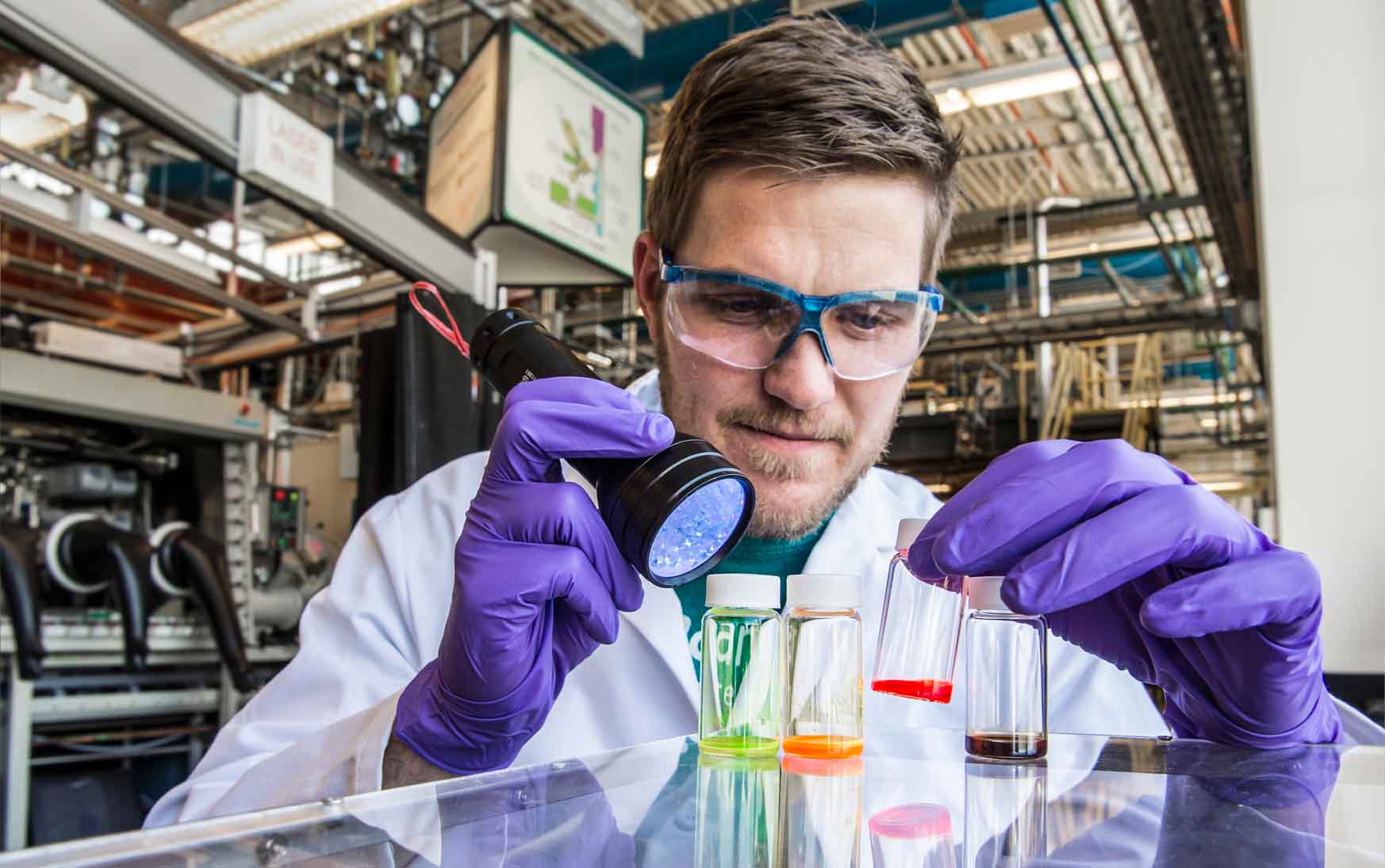 Photo of a man in a lab coat looking at vials.