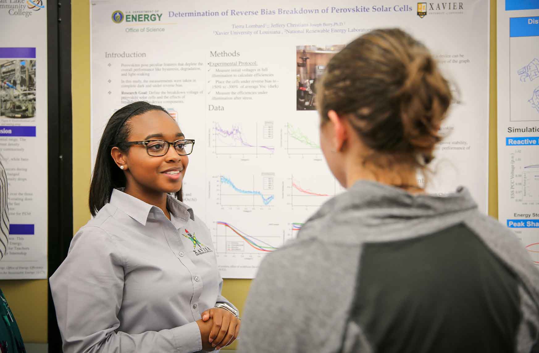 Two women talk in front of a science poster.