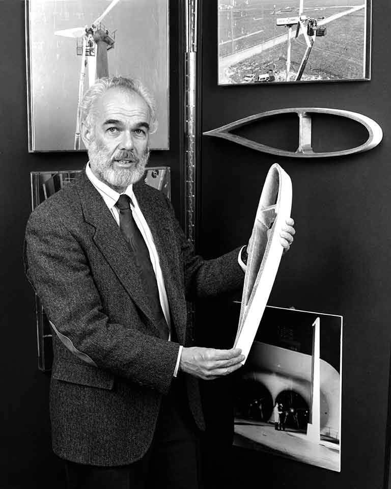 A man holds a model of a section of a wind turbine foil.