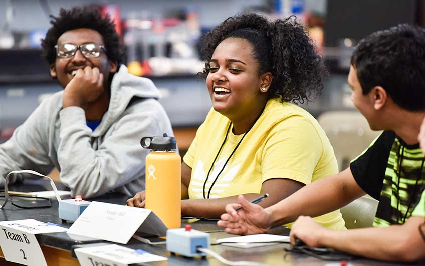 Three students, two boys and one girl, relax after a correct answer in one of the early-round matches during the 2018 Colorado High School Science Bowl.