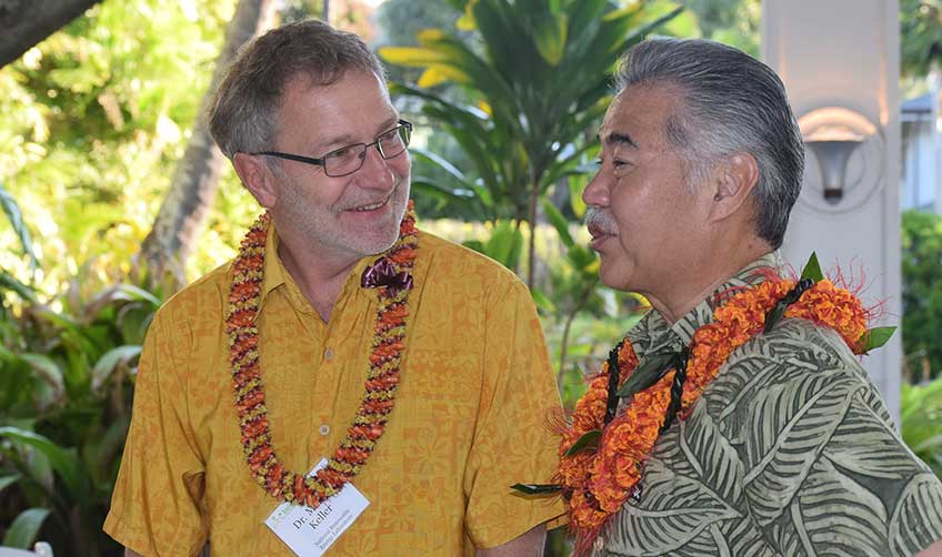 Photo of two men wearing Hawaiian shirts and flower leis.