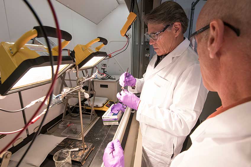 Energy Secretary Rick Perry uses a small paintbrush to make a solar cell.