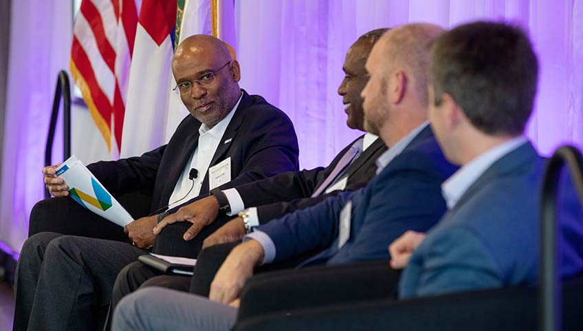 The panel moderator listens to another panelist.