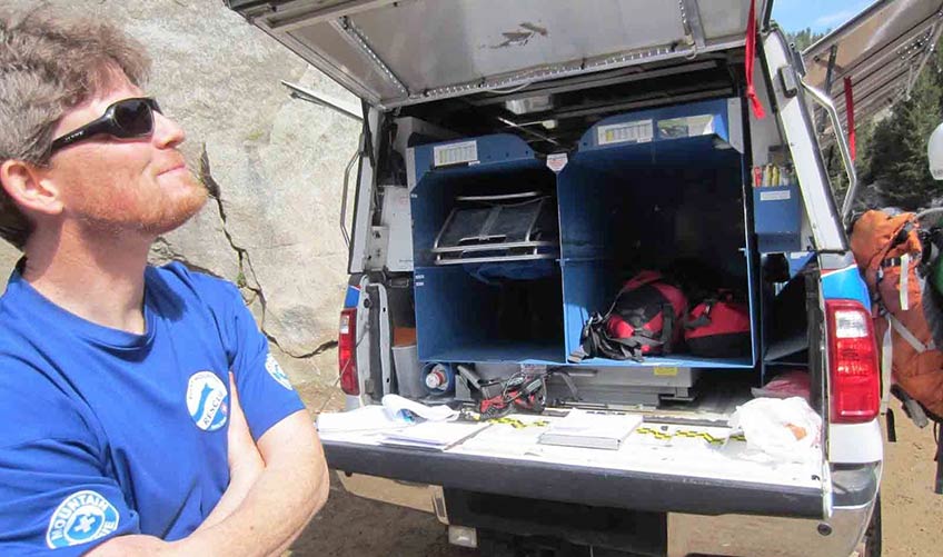 A man stands near an emergency vehicle outdoors.