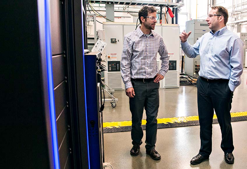 Two men talk in a laboratory.