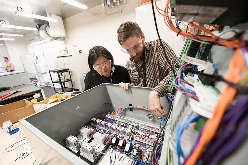 Two researcher looking over their hardware prototype. 