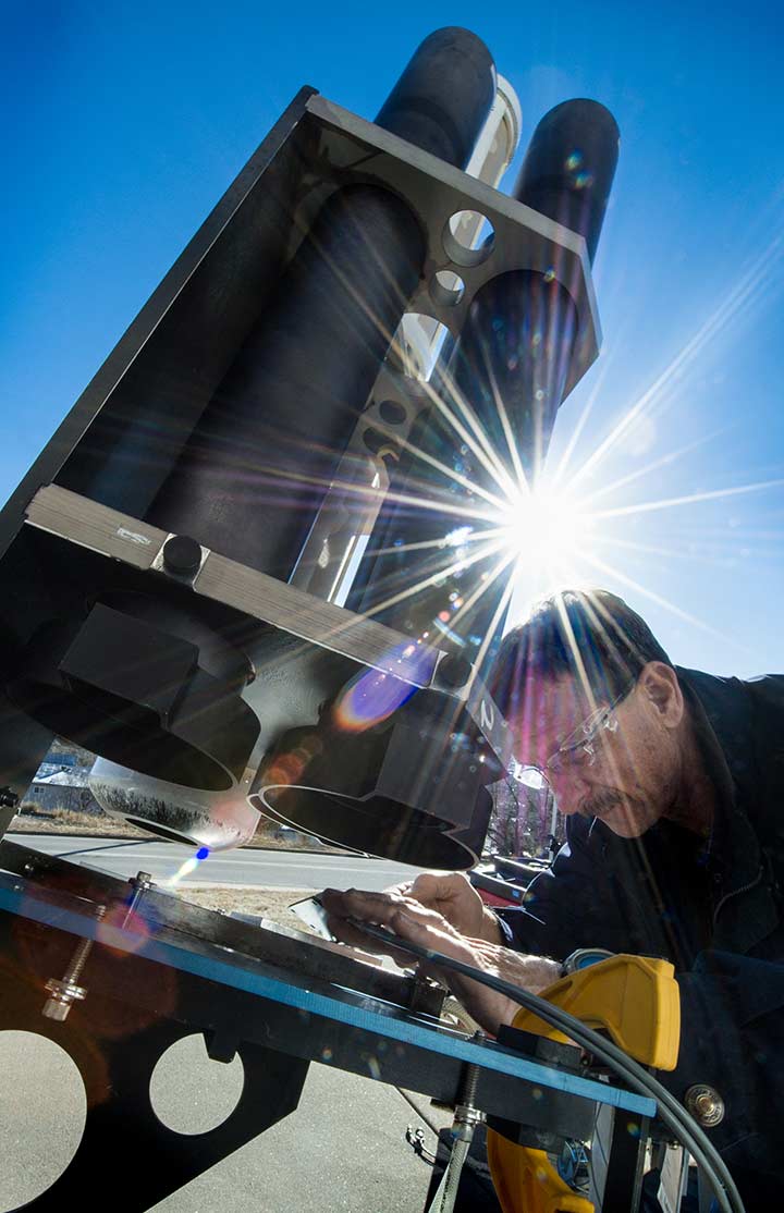 A man examines a piece of equipment outside.