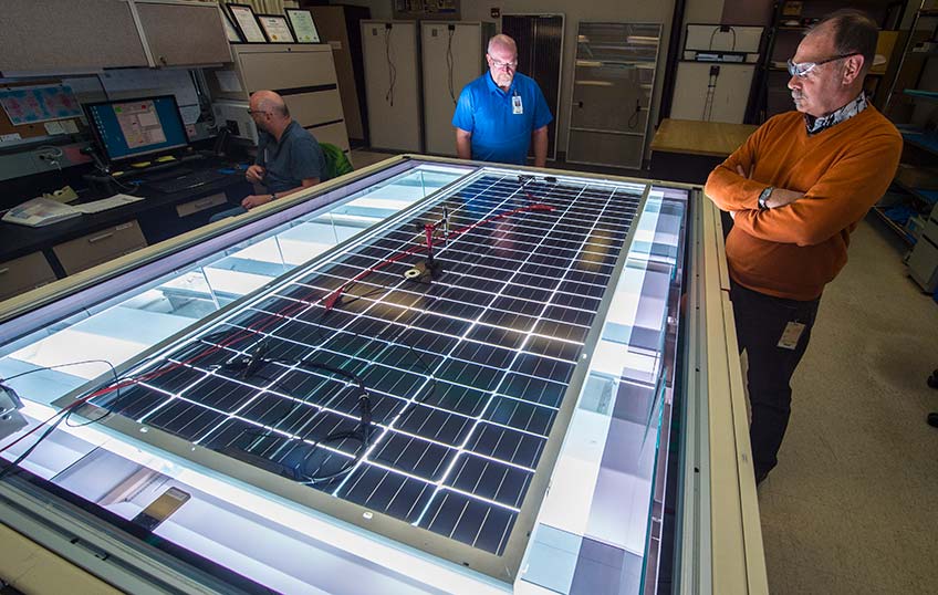 Two men looking at a solar panel setup displayed on a table