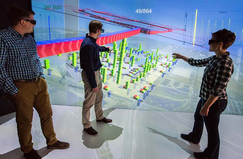 Three researchers look at a data visualization projected on wall