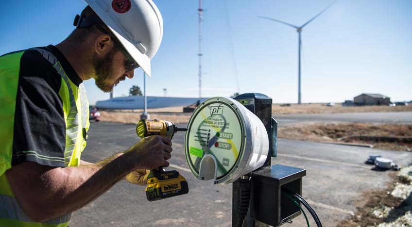 Photo of a man using a power drill to install an electric vehicle charging station.