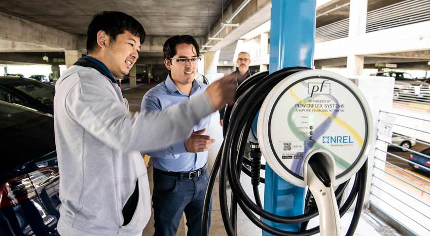 Two researchers look at an installed charger in parking garage