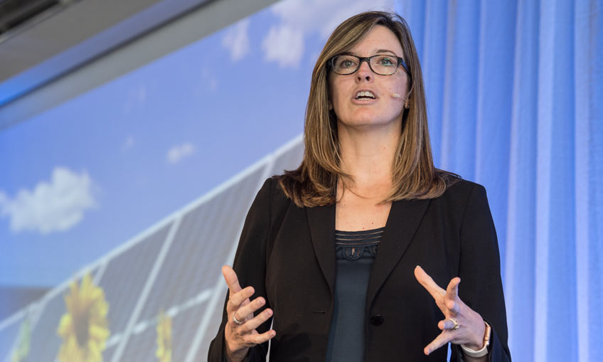 Photo of a woman speaking on a stage.