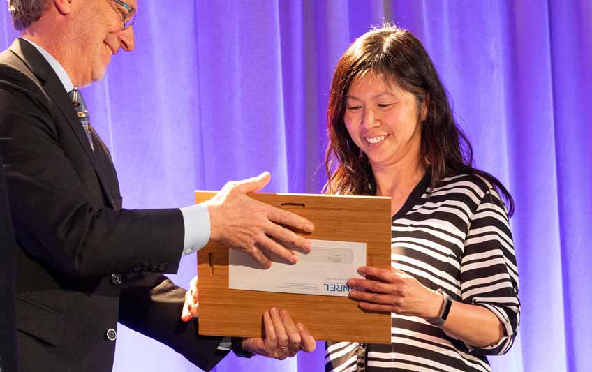 Photo of a man presenting an award plaque to a woman.