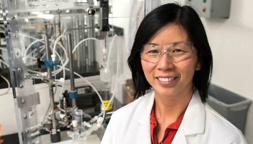 Photo of a woman wearing a lab coat and standing in a laboratory.