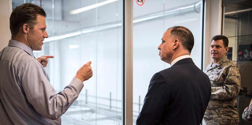 Photo of two men talking while a military man looks on.